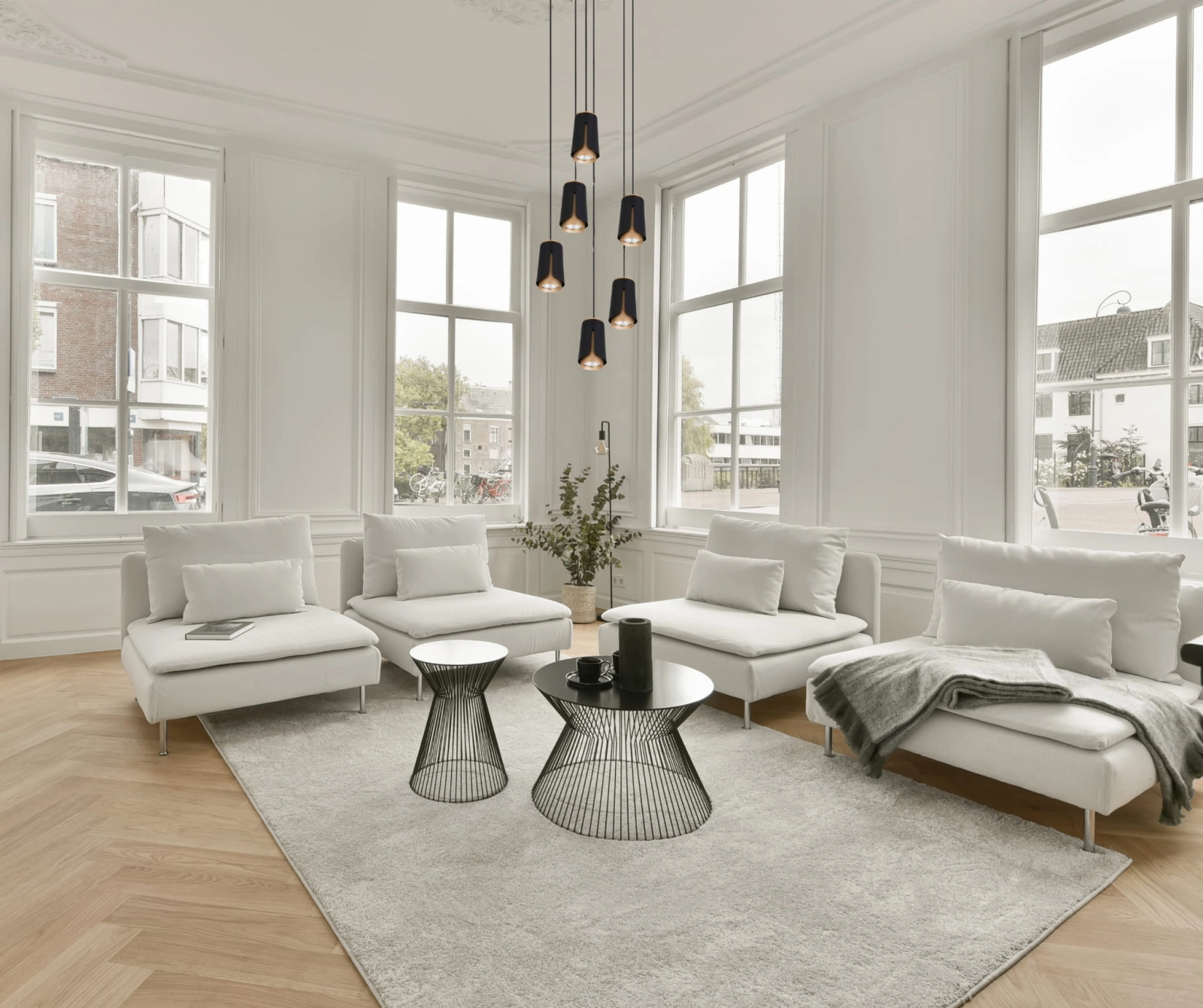 czarno złota lampa flower 6 zawieszona w dużym białym salonie.
