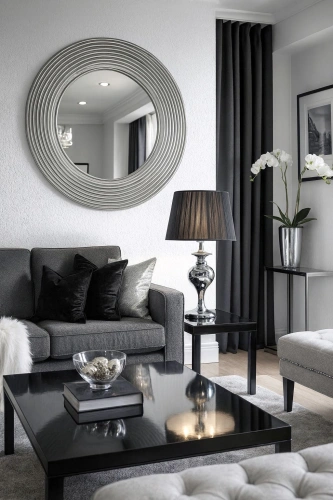 Lampka stołowa Gillenia z chromowaną podstawą i czarnym abażurem w eleganckim salonie glamour, obok szarej sofy, okrągłego lustra i dekoracyjnych dodatków w odcieniach srebra i czerni.