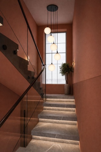 Lampa z pięcioma kloszami zawieszona przy schodach.
